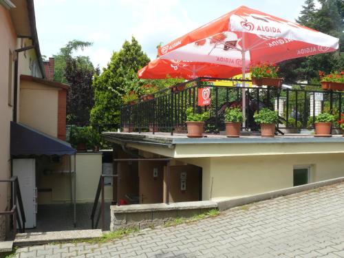 a patio with a red umbrella and potted plants at Penzion Dana Troja in Prague
