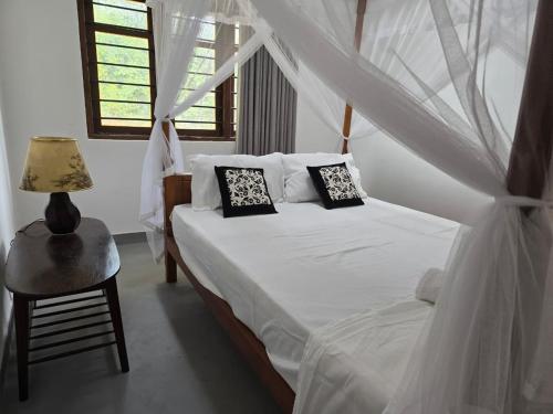a bedroom with a bed with white sheets and pillows at Shayon Villa in Hiriketiya