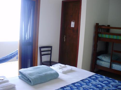a bedroom with a bed and a chair and a door at Pousada Piquara in Mangaratiba