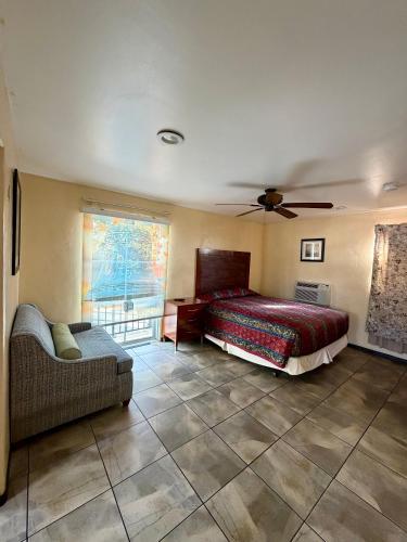 a bedroom with a bed and a couch and a ceiling fan at Mission Bell Motel in Ventura