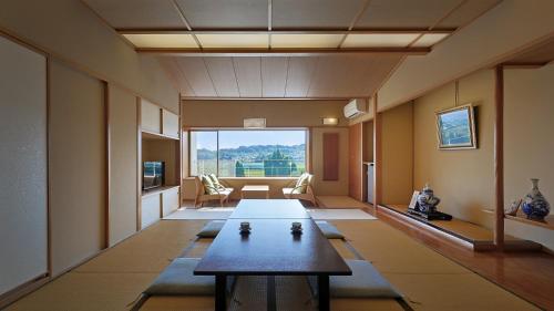 a living room with a table and a large window at Hotel Symphony Annex Sagae Onsen in Sagae