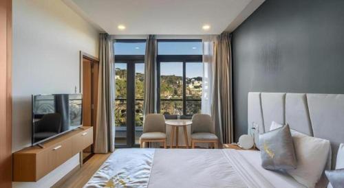 a bedroom with a bed and a table with chairs at Gold View Boutique Hotel Đà Lạt in Xuan An