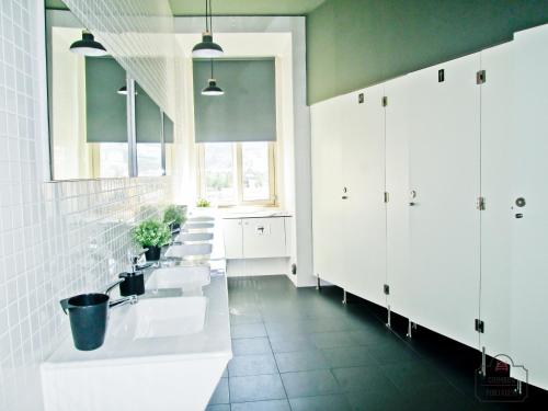 uma casa de banho com três lavatórios e armários brancos em Coimbra Portagem Hostel em Coimbra