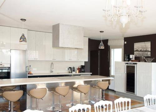 a kitchen with white cabinets and bar stools at Gite Bobinou in Lisbourg