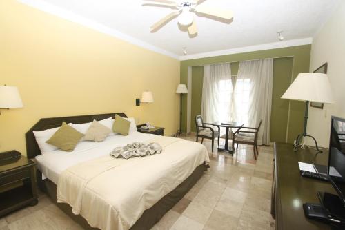 a bedroom with a large white bed with a ceiling fan at Hotel Los Itzaes by 5th av in Playa del Carmen