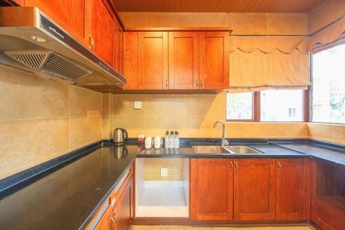 a kitchen with wooden cabinets and a sink at Country Garden Holiday Hotel Fogang Hot Spring in San-pa