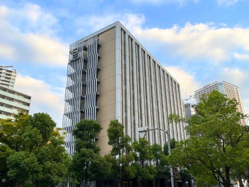 a tall white building with trees in front of it at Hotel Gracery Tokyo Tamachi in Tokyo