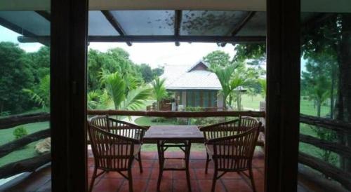 eine Terrasse mit Tisch und Stühlen auf einer Veranda in der Unterkunft Chiangkham Luang Resort in Ban Huai Sai
