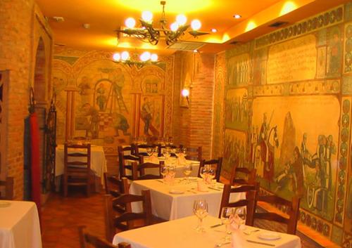 un restaurante con mesas y sillas blancas y un mural en Hospederia Fernando I, en León
