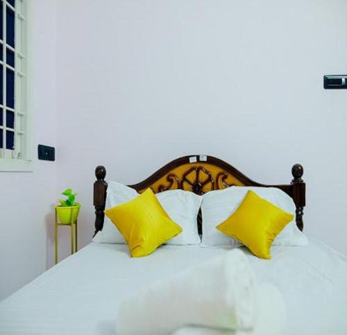 um quarto com uma cama branca com travesseiros amarelos em The Sunshine Villa em Pondicherry