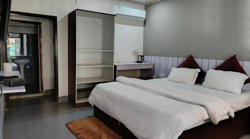 ein Schlafzimmer mit einem großen Bett mit weißer Bettwäsche in der Unterkunft Barhoitoka Homestay in Kāziranga