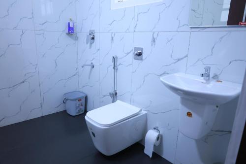 Un baño blanco con inodoro y lavabo. en Red cloud munnar, en Munnar