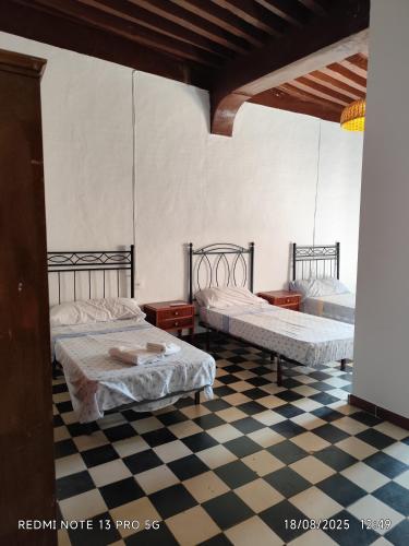 two beds in a room with a checkered floor at Gustavo's Old House in Fiñana