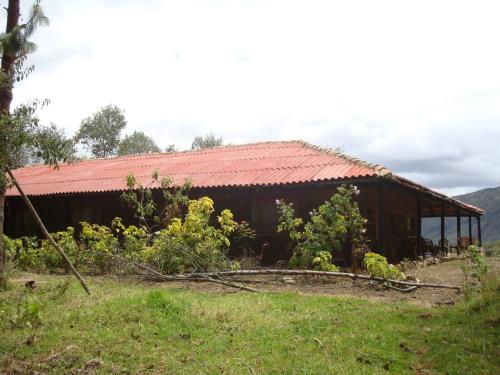 a building with a red roof in a field at Monzaque- paraíso de bachué in El Barrial