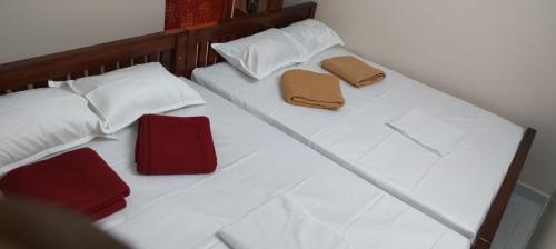 ティルヴァンナーマライにあるGuru Roomsの白いベッド(赤い枕2つ付)