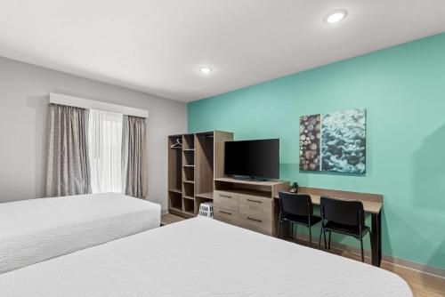 a hotel room with two beds and a desk with a tv at Echo Suites Extended Stay by Wyndham Atlanta-Conyers in Conyers
