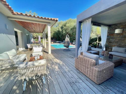 una terrazza in legno con mobili in vimini e una piscina di meli melo a Mangialla