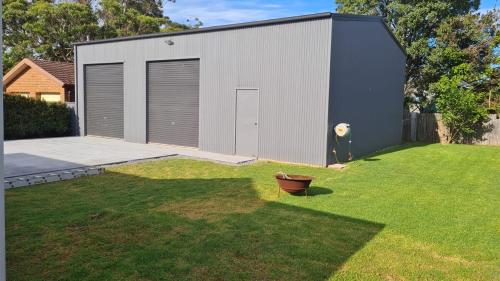 a building with a door on the side of a yard at The Burra Spa, Games & Beach House in Culburra Beach