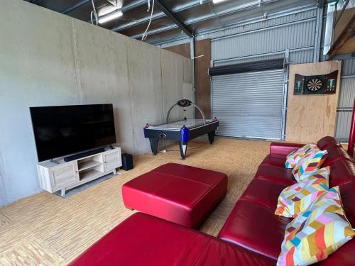 a living room with a red couch and a flat screen tv at The Burra Spa, Games & Beach House in Culburra Beach