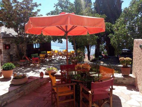 a table with a red umbrella on a patio at Archontiko Pantou in Portaria
