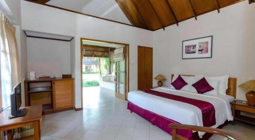 a bedroom with a large bed and a television at Tanjung Lesung Beach Hotel in Kalicaah