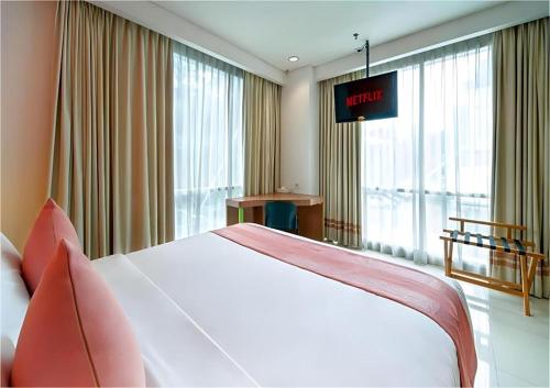a hotel room with a bed and a large window at Pomelotel Patra Kuningan Jakarta in Jakarta