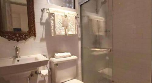 a bathroom with a toilet and a sink and a shower at Avenue Suites in Bacolod