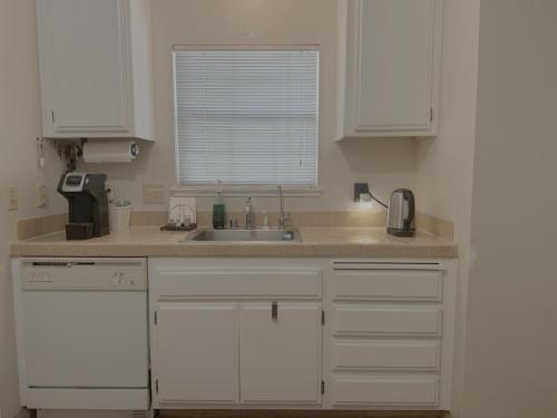 a kitchen with white cabinets and a sink and a window at Fan's Family in Tracy