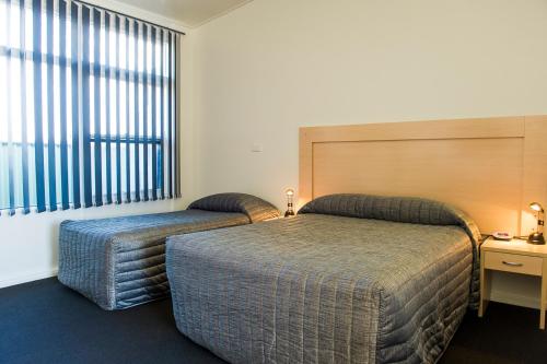 a bedroom with two beds and a desk and a window at Cherry Blossom Motor Inn in Young