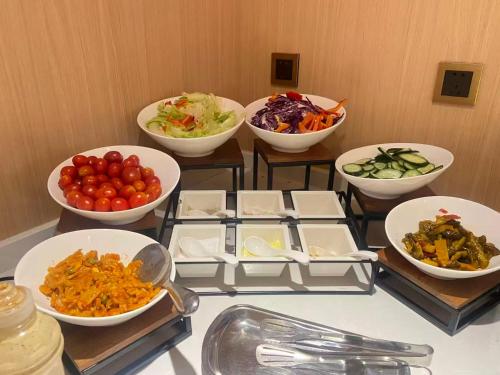 a table with bowls of food and bowls of vegetables at Dequan Luxury Hotel National Exhibition Center Wangjing Bridge Branch The subway is right outside the door Coffee, snacks, a gym and a laundry room are provided for free in the lobby in Beijing