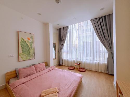 a bedroom with a pink bed and a large window at The Hideout Stay in Hanoi