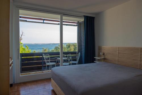 莫尼加Casa dei limoni Steps to Garda Lake的一间卧室配有一张床,阳台配有桌椅