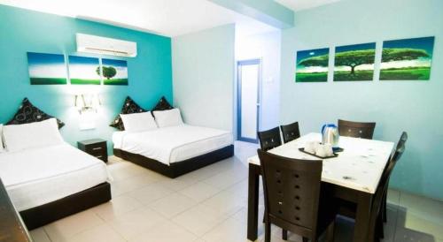 a room with two beds and a table and a bed and a dining room at Pice Hotel in Kampong Permatang Batu