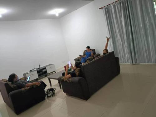 a group of people sitting on couches in a living room at OYO HOME 90769 Flo Inn Homestay Bsi in Kampong Parit