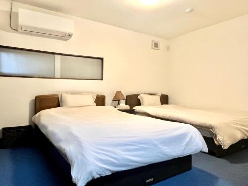 a room with two beds and a air conditioner at CatNook 猫ちぐら in Matsumoto