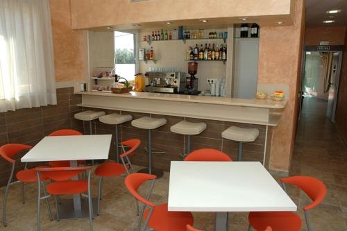 a bar with white tables and red chairs in a restaurant at Hostal Los Coronales in Madrid