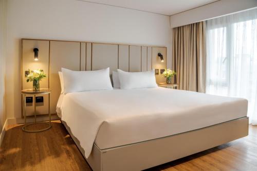 una cama blanca grande en una habitación de hotel en NH Boulevard del Río Cali, en Cali