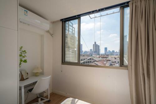 Zimmer mit einem Schreibtisch und einem Fenster mit Aussicht in der Unterkunft HuanYu in Shanghai