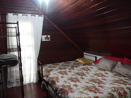 a bedroom with a bed and a wooden wall at Casa no Bosque Vila Natal in Campos do Jordão