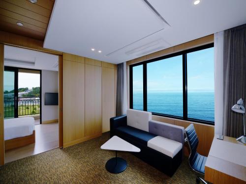 a room with a couch and a bed and a window at Ramada by Wyndham Gangwon Sokcho in Sokcho