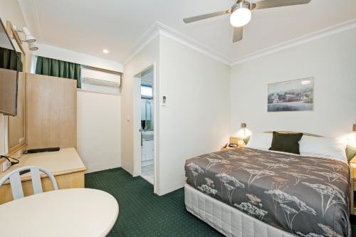 a hotel room with a bed and a desk and a table at Colonial Terrace Motor Inn in Raymond Terrace