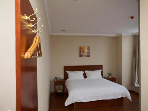 a bedroom with a bed with white sheets at GreenTree Inn Hefei Huangshan Road Business Hotel in Hefei
