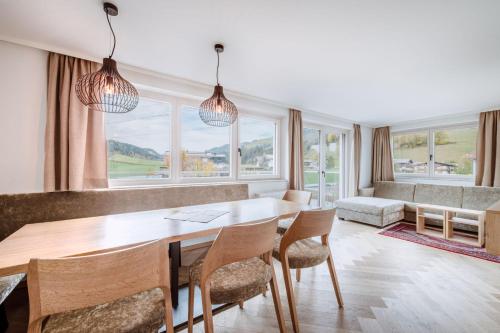 a dining room with a table and chairs and windows at Harmls Aparthotel in Flachau