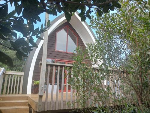 a small house with a wooden deck and a window at Private cozy timber chalet with fireplace in Raglan
