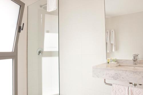 a white bathroom with a sink and a shower at Hotel Patagonia Sur in Cádiz