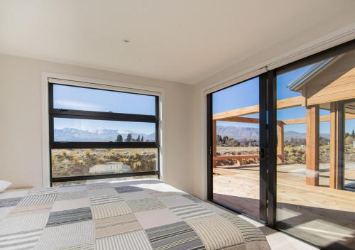 a bedroom with a bed and large windows at Mackenzie Crib in Lake Tekapo