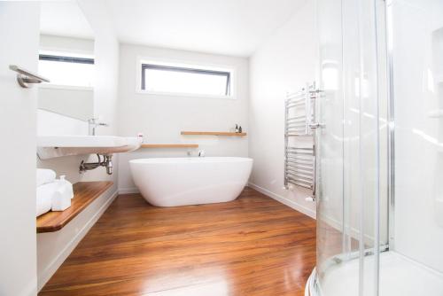 a white bathroom with a tub and a sink at Mackenzie Crib in Lake Tekapo