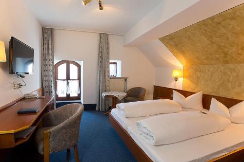a bedroom with a bed and a desk and a computer at Hotel am Markt in Greding