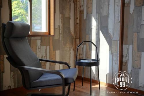 Ein Stuhl und ein Tisch vor einer Wand in der Unterkunft Route 99 Sengokuhara in Sengokuhara