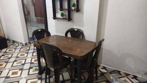 Una mesa y sillas de madera en una habitación. en Shaan's Homestay, en Jorhat